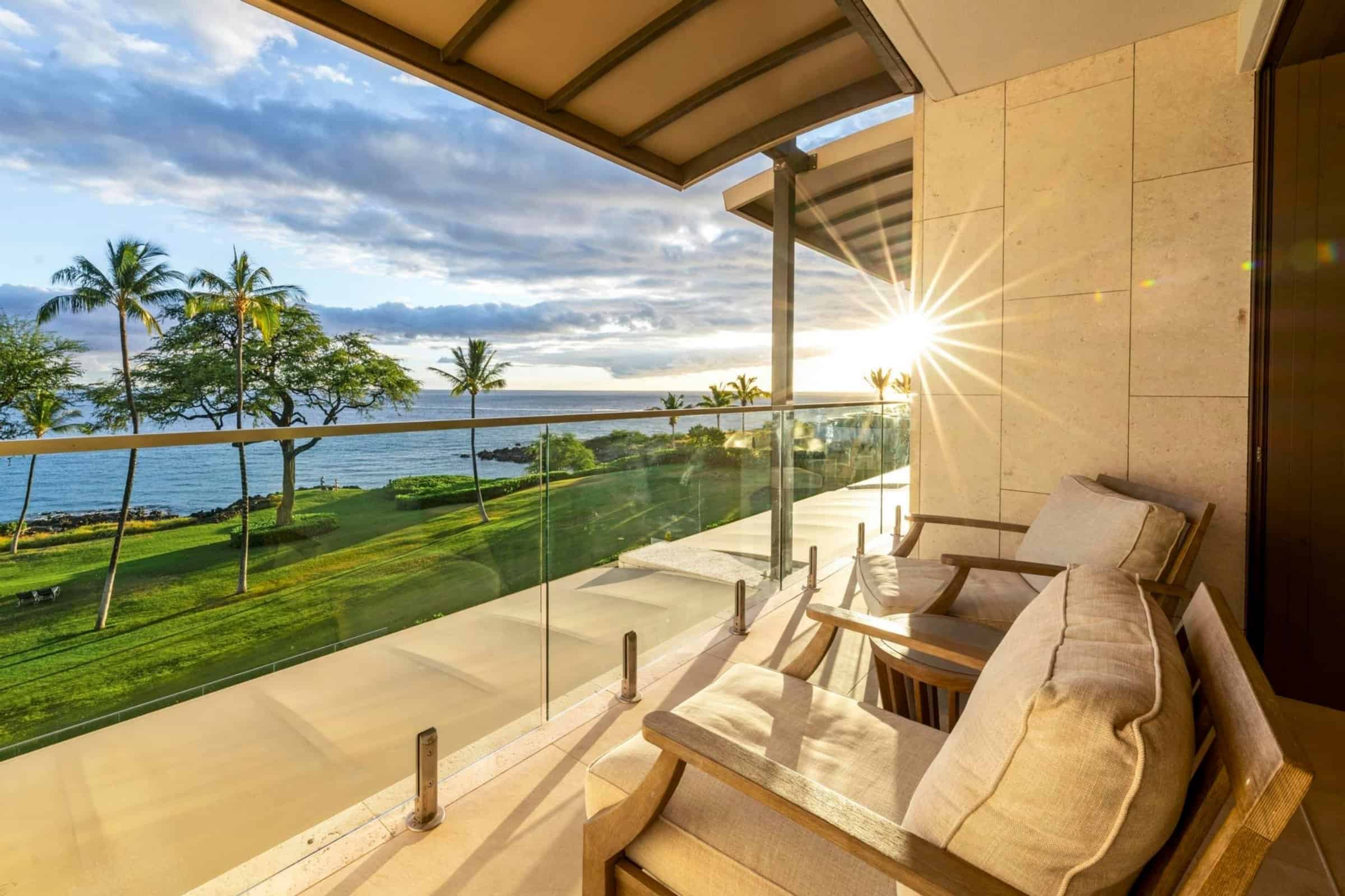 Oceanfront condo in Kona with stunning sunset views and lush landscape.