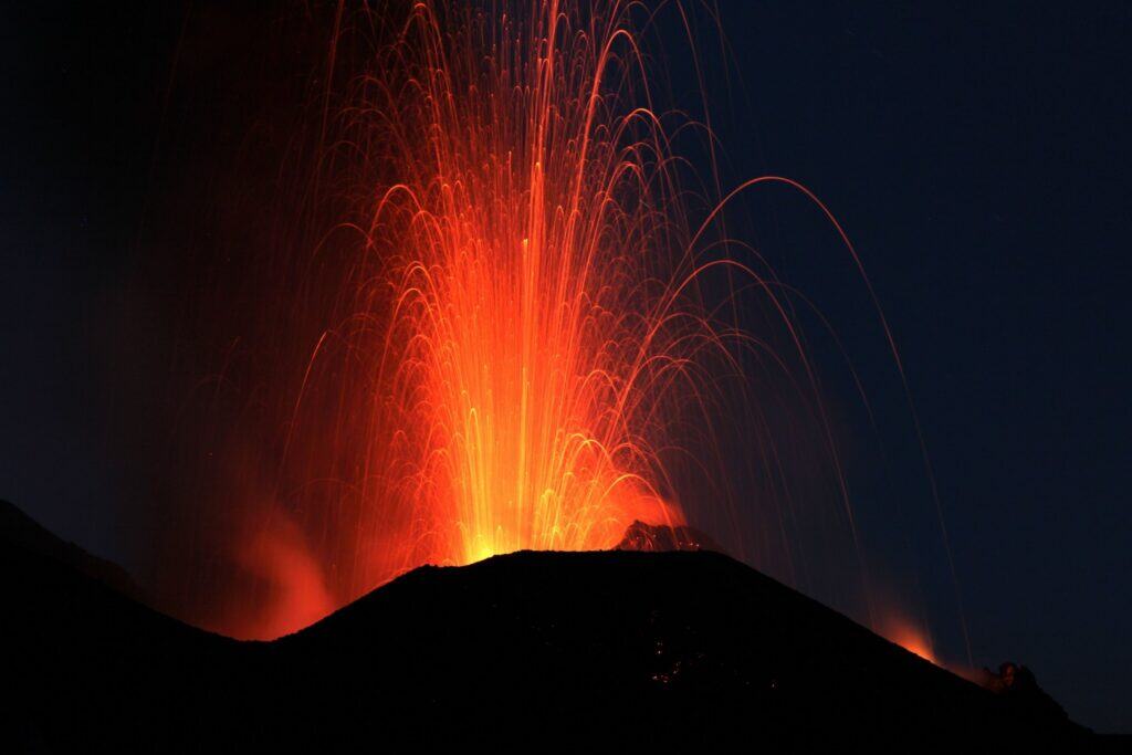 Nighttime volcanic eruption in Big Island Hawaii with flowing lava and fiery sparks.