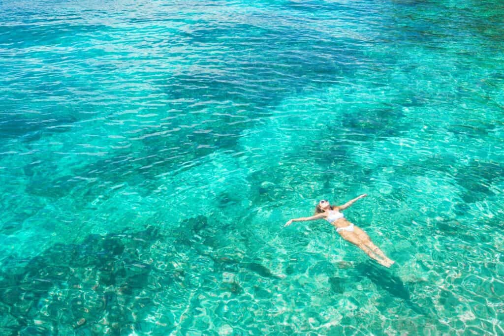 Woman relaxing in clear turquoise waters on Big Island, Kona, Kohala Coast lifestyle.