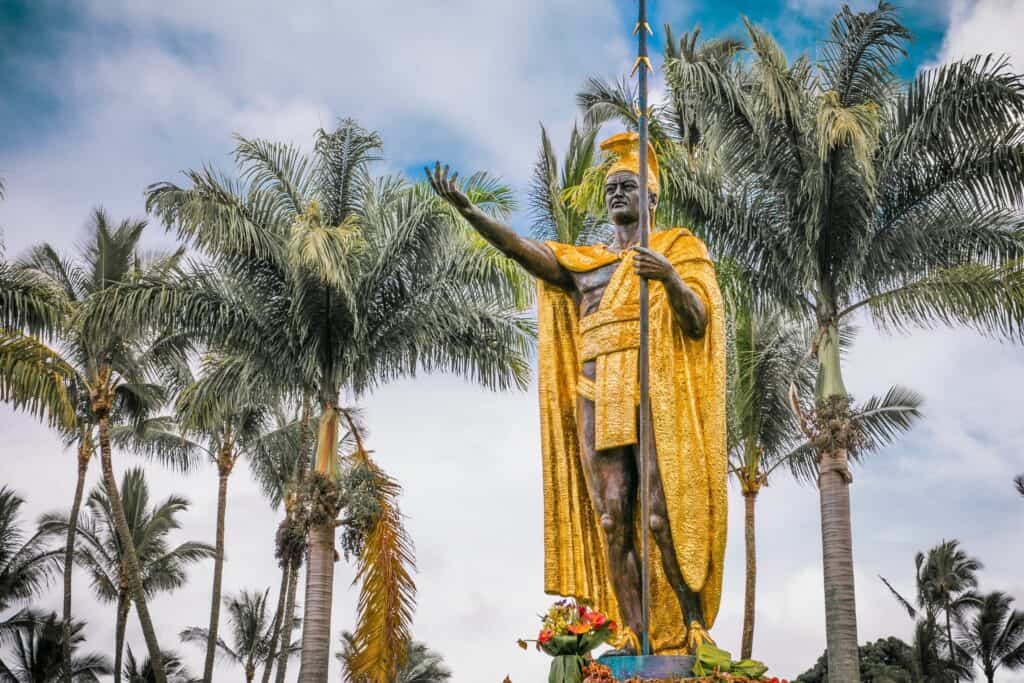Iconic Big Island Hawaii statue with palm trees in the background.