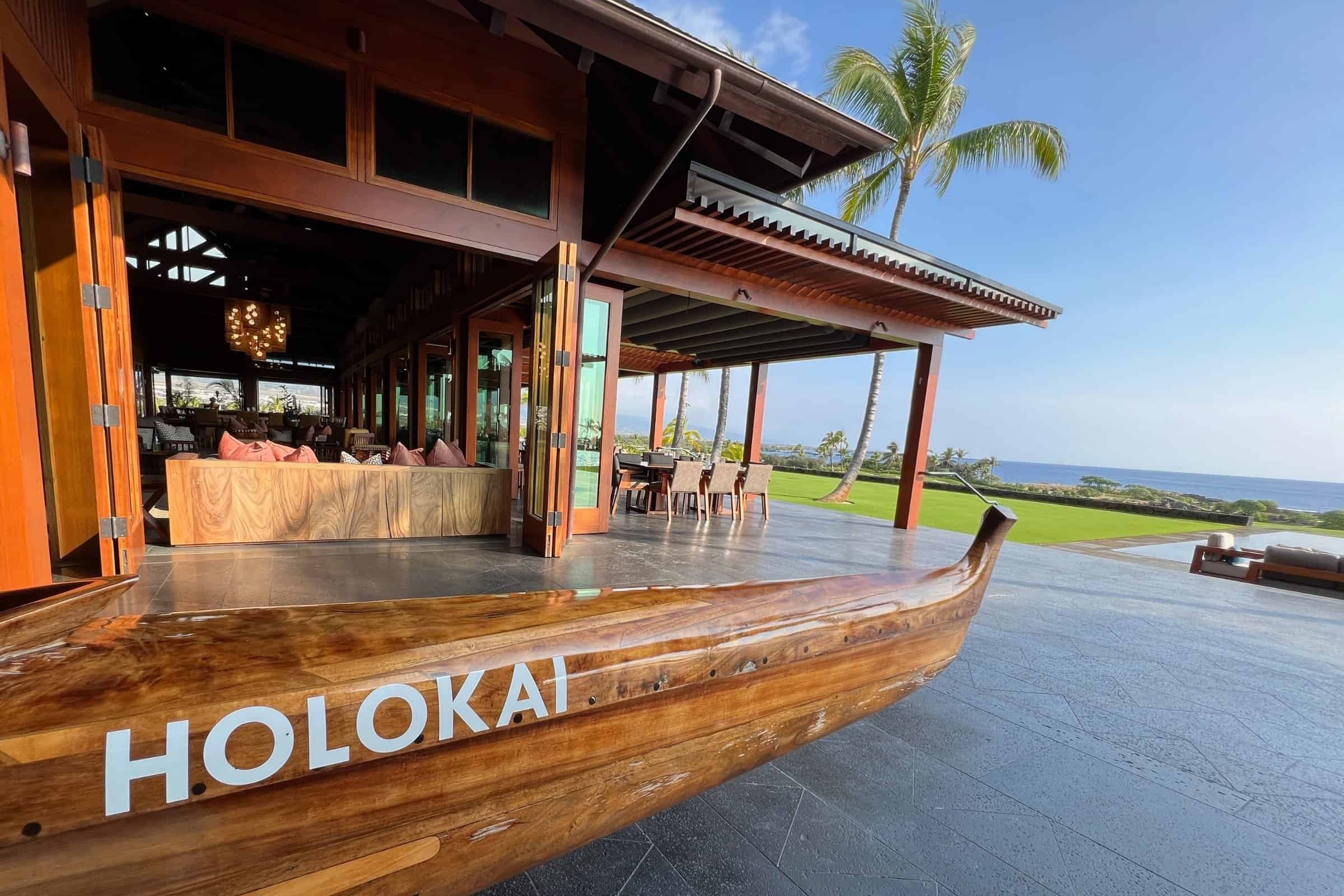 Open air clubhouse at Kohanaiki with a koa canoe in the foreground and the ocean beyond.