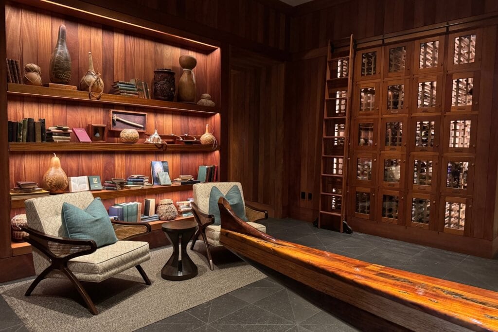 Dark wood panelled library with built in shelving and seating in a Kohanaiki residence.