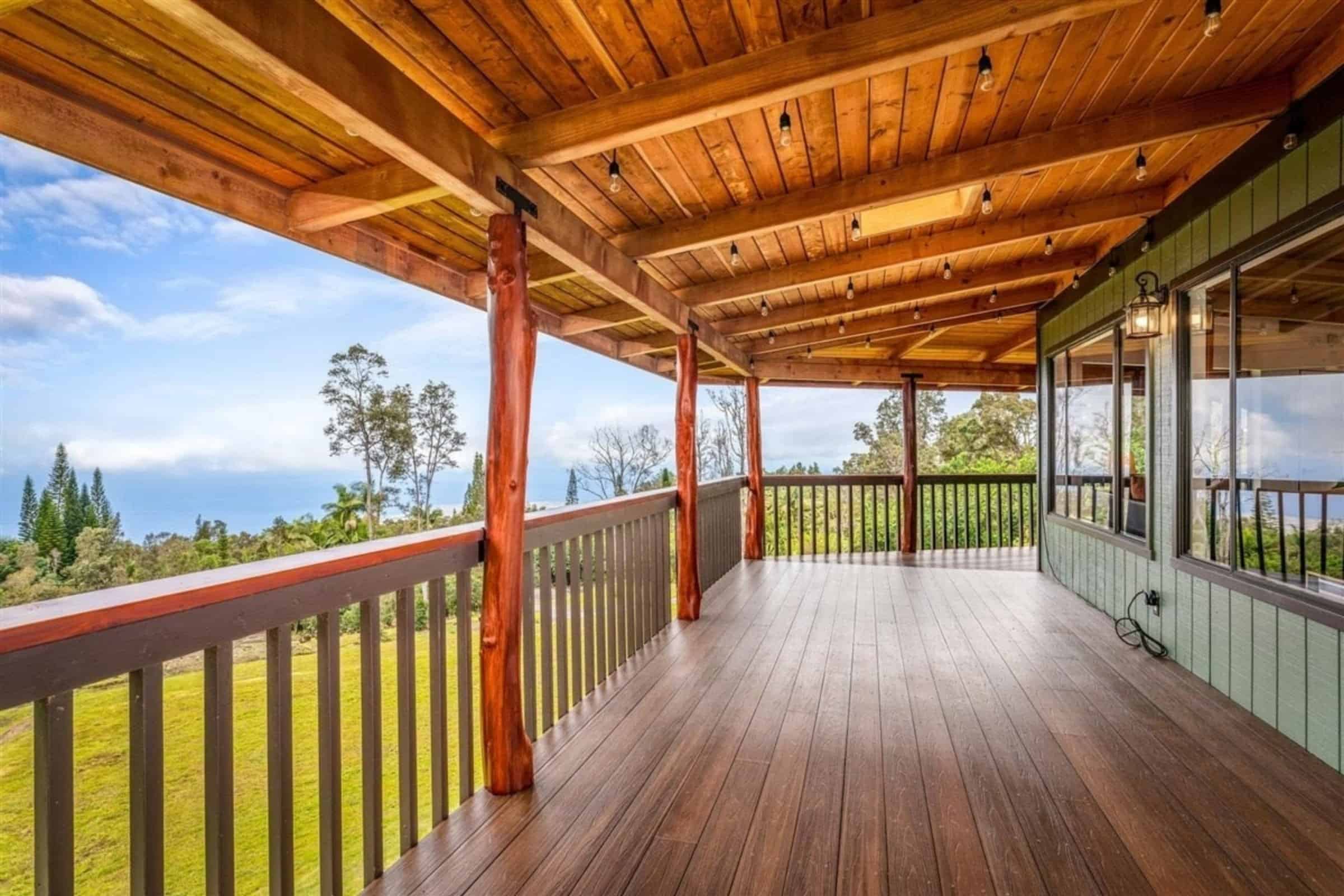 Balcony of a Big Island Hawaii home overlooking lush landscape and ocean, perfect for Kona and Kohal.
