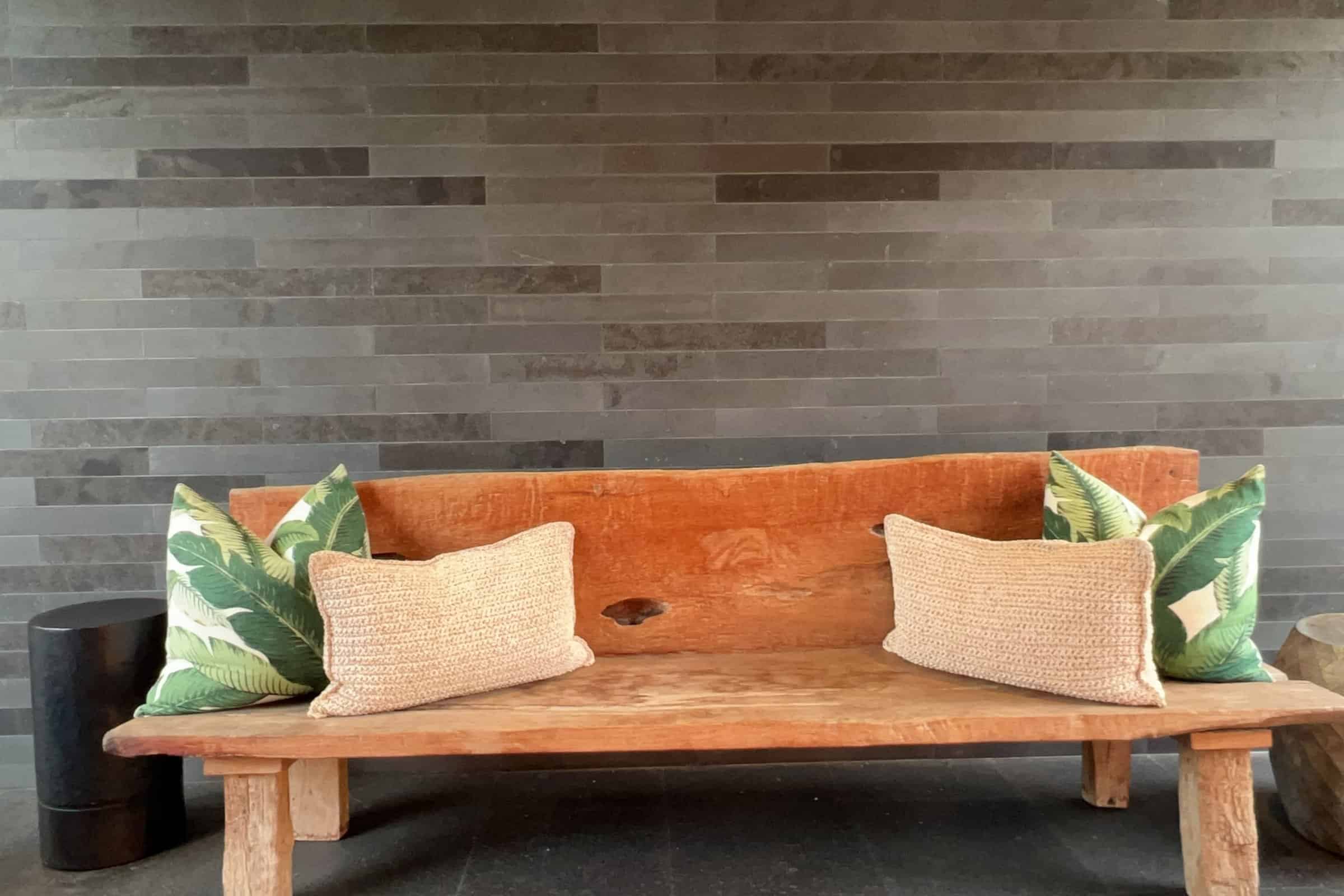 Outdoor wooden bench with tropical pillows, perfect for relaxing on Hawaii's Big Island.