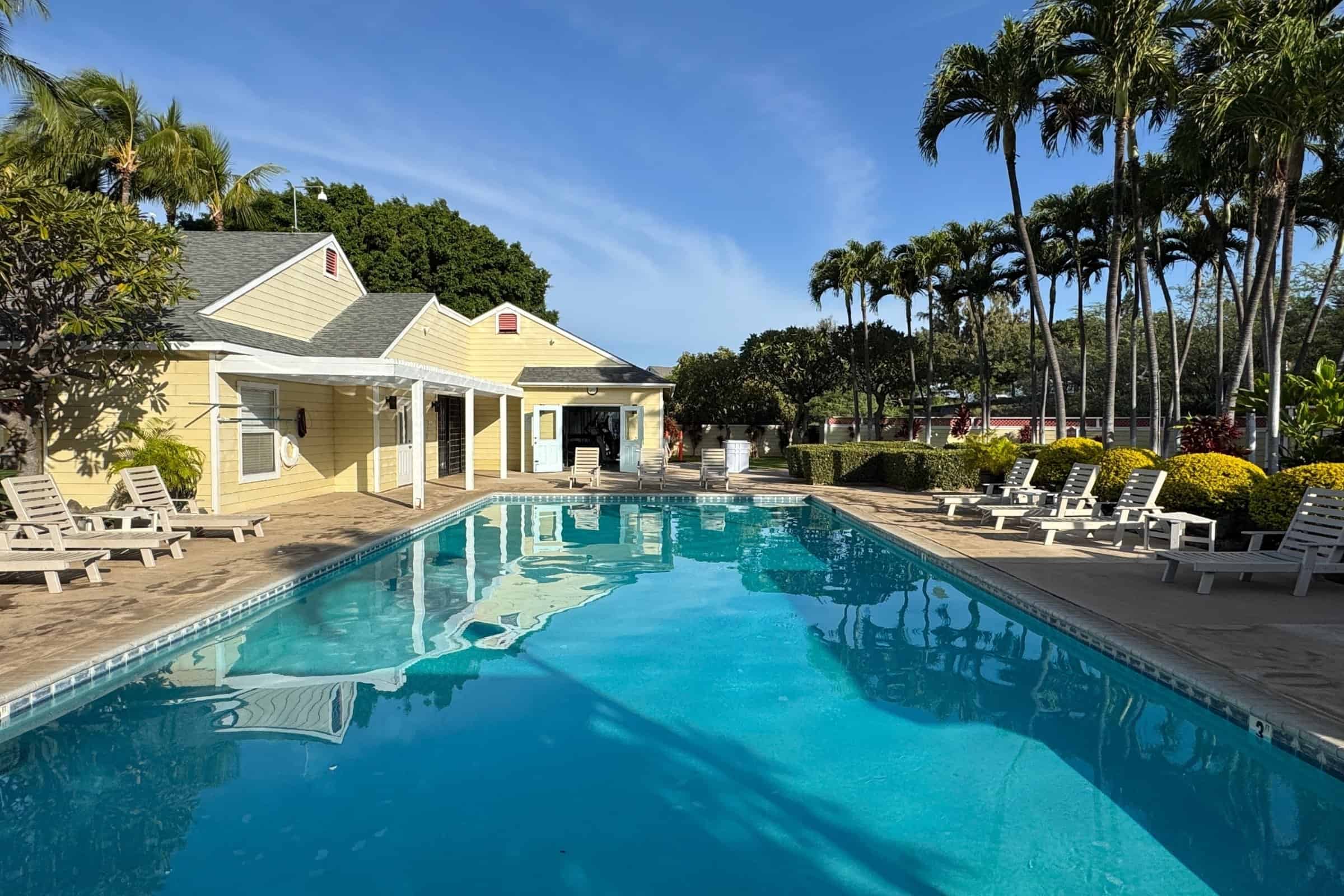 Poolside view of a luxury home in Kona with tropical landscaping and ocean breeze.