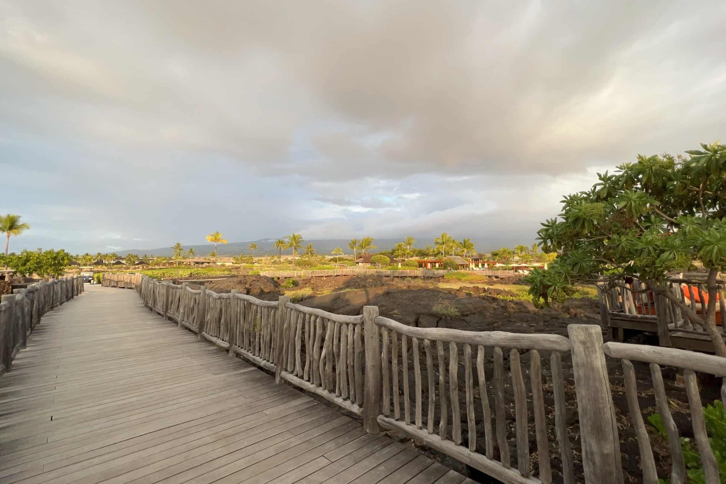 Oceanview walkway along Big Island Hawaii coast with lush greenery and volcanic landscape.