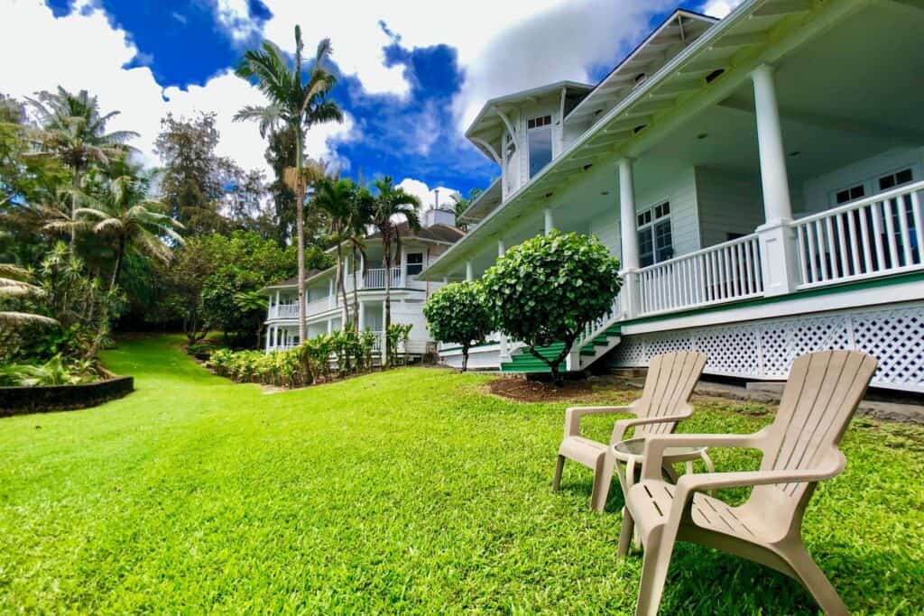 Luxury oceanfront home in Kona with lush tropical landscaping and outdoor seating.