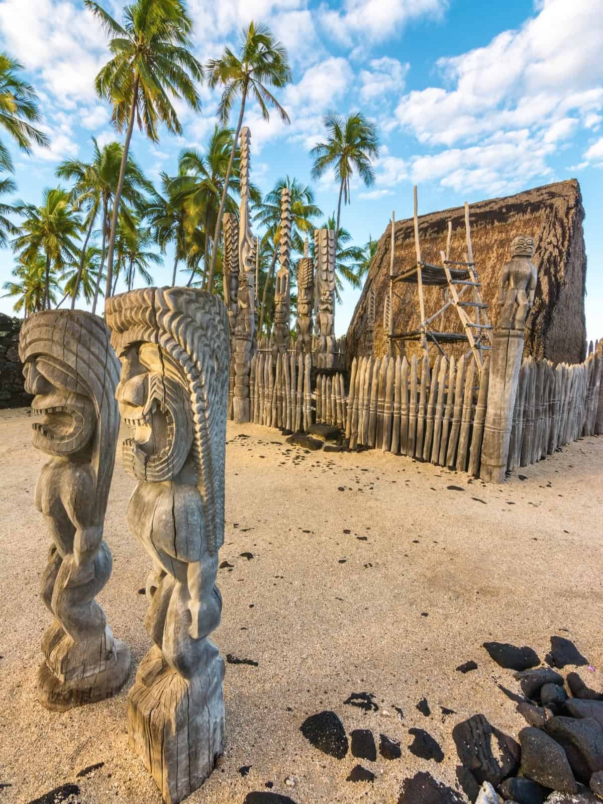 Beachfront estate in Honaunau with tropical palms and traditional Hawaiian carvings.