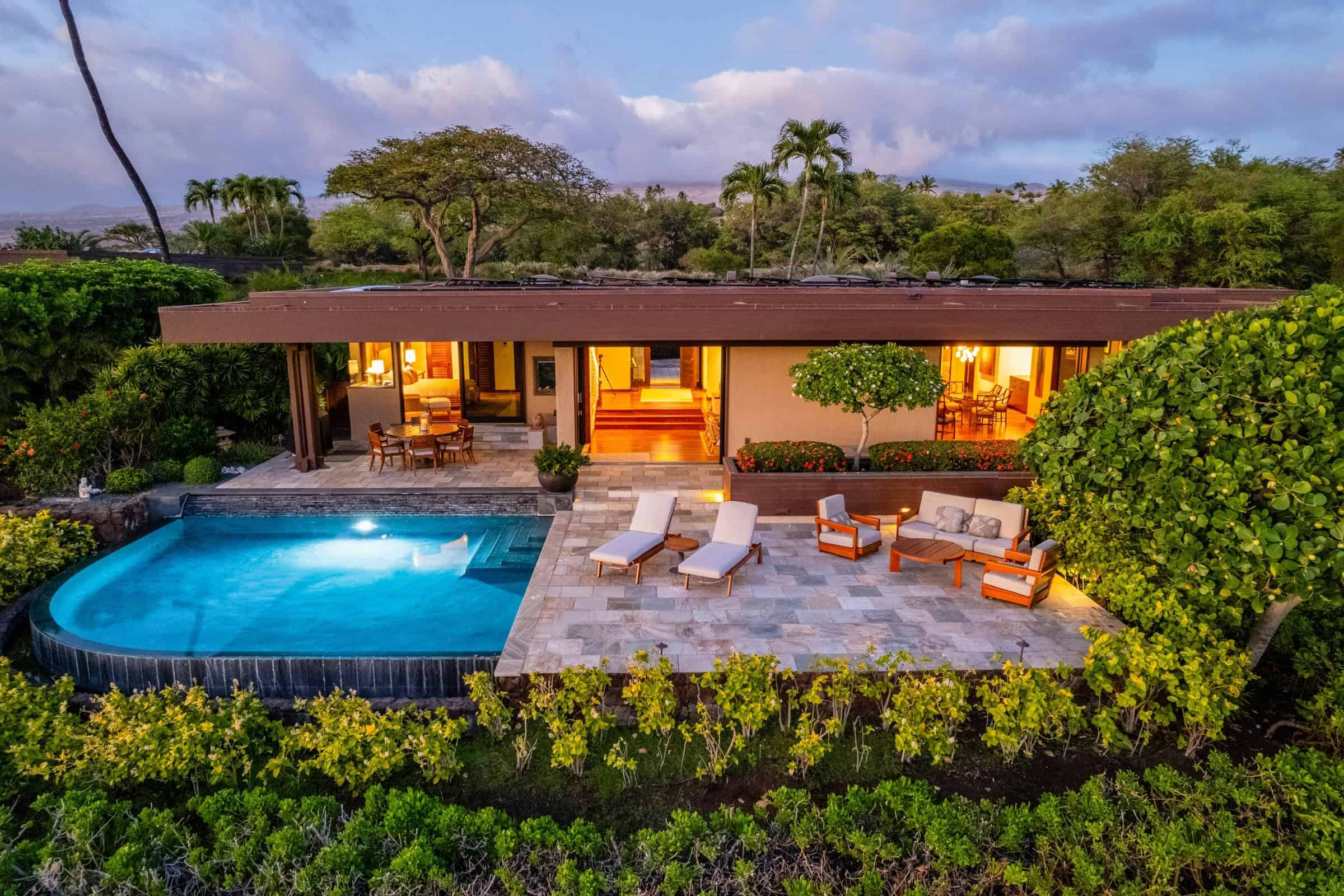 Lit pool and lounge chairs at dusk beside a villa at Mauna Kea Resort.