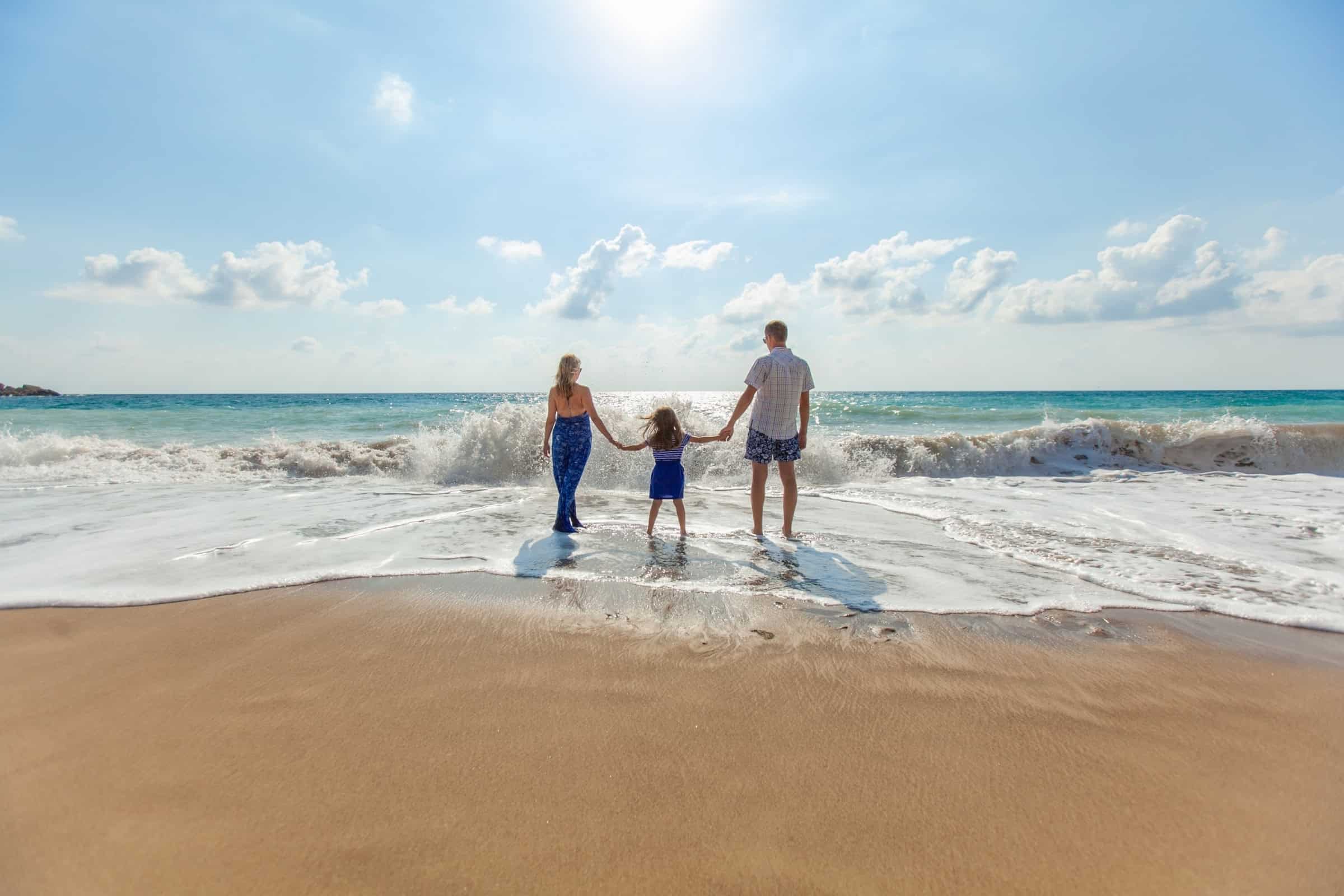 Family walking into the surf together on a Big Island beach.