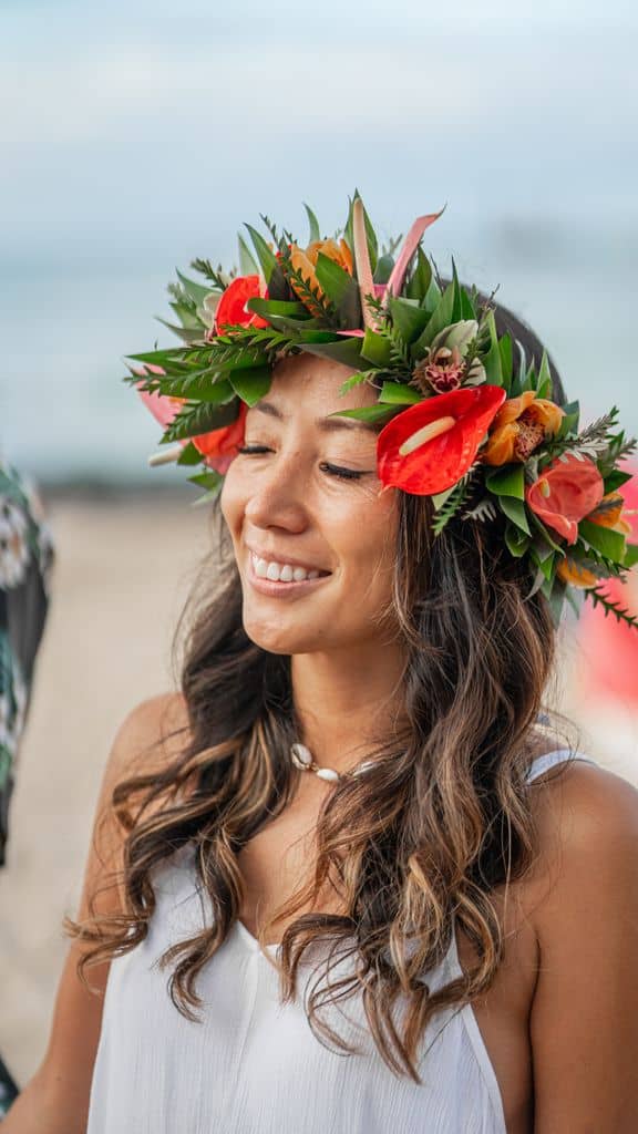Woman smiling in a haku lei of red anthurium and tropical blooms.