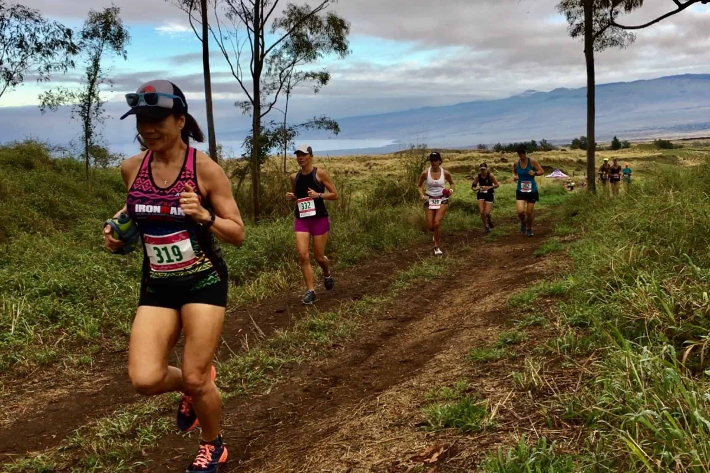 Trail runners on dirt singletrack above the ocean at the Hearts and Trails race in Kona.