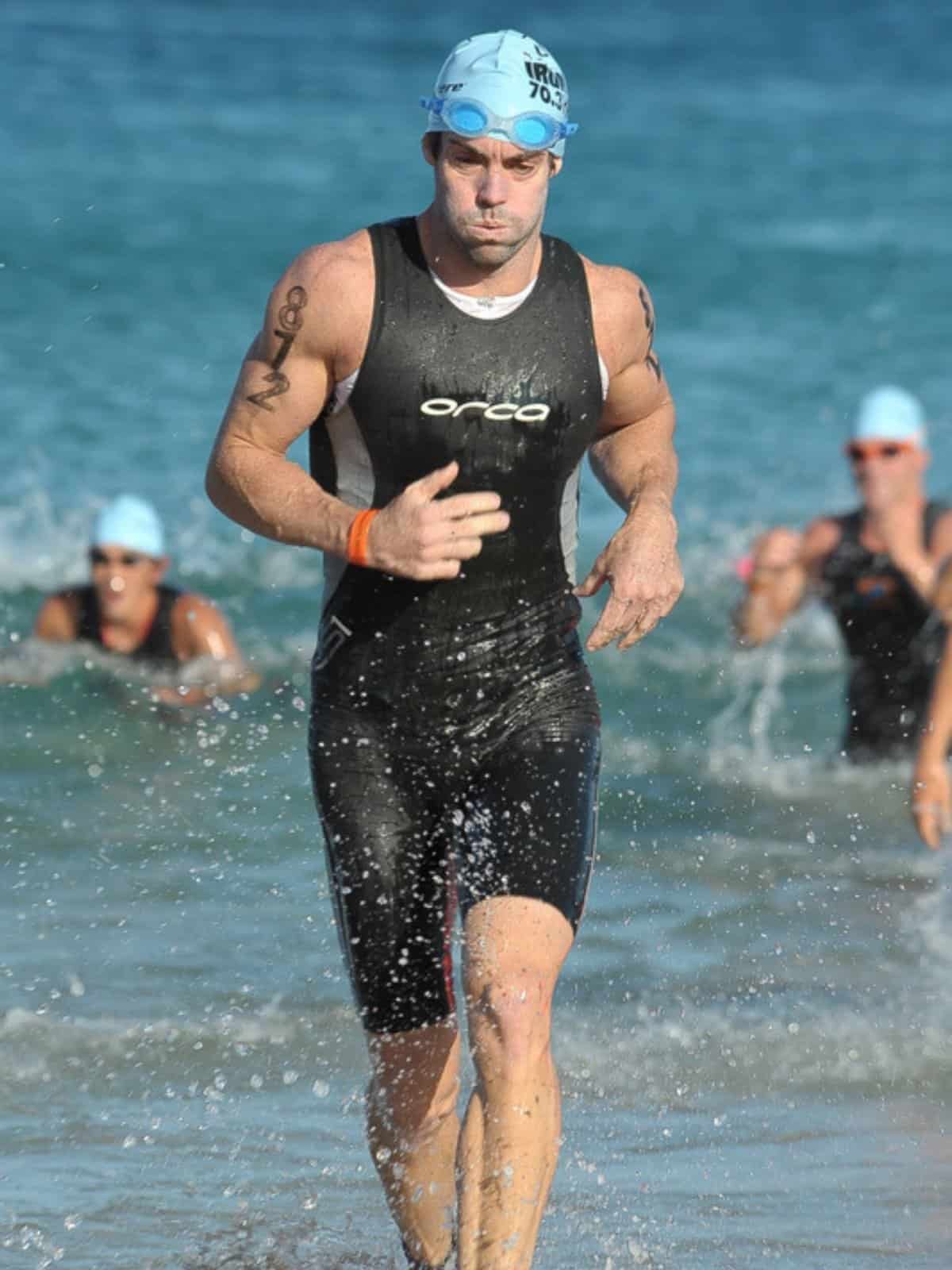Swimmer exiting the water in cap and goggles at the Honu 70.3 swim finish.