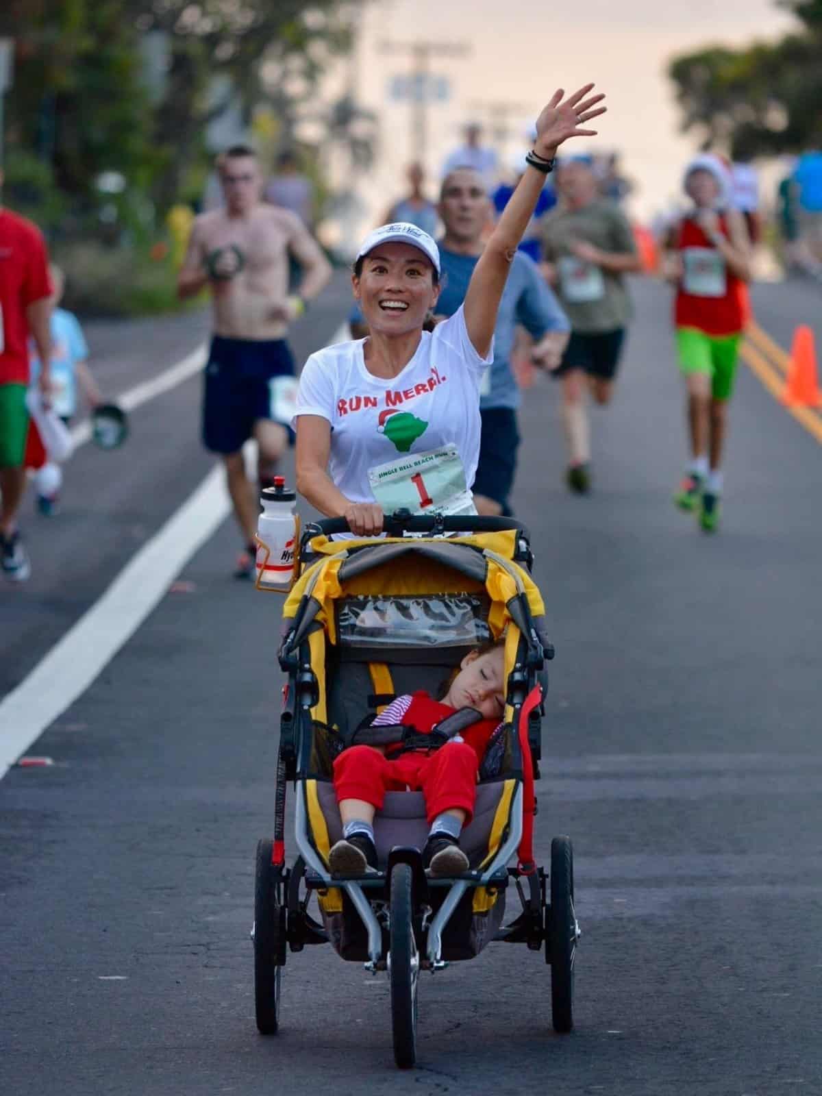 Runner pushing a jogging stroller through the field at a Kailua-Kona road race.