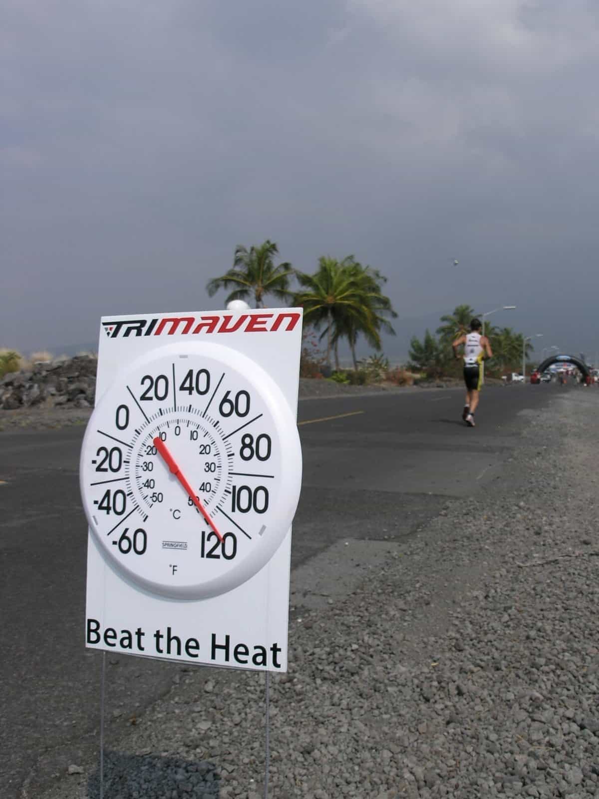 Course thermometer beside a runner on the hot highway pavement during a Kona triathlon.