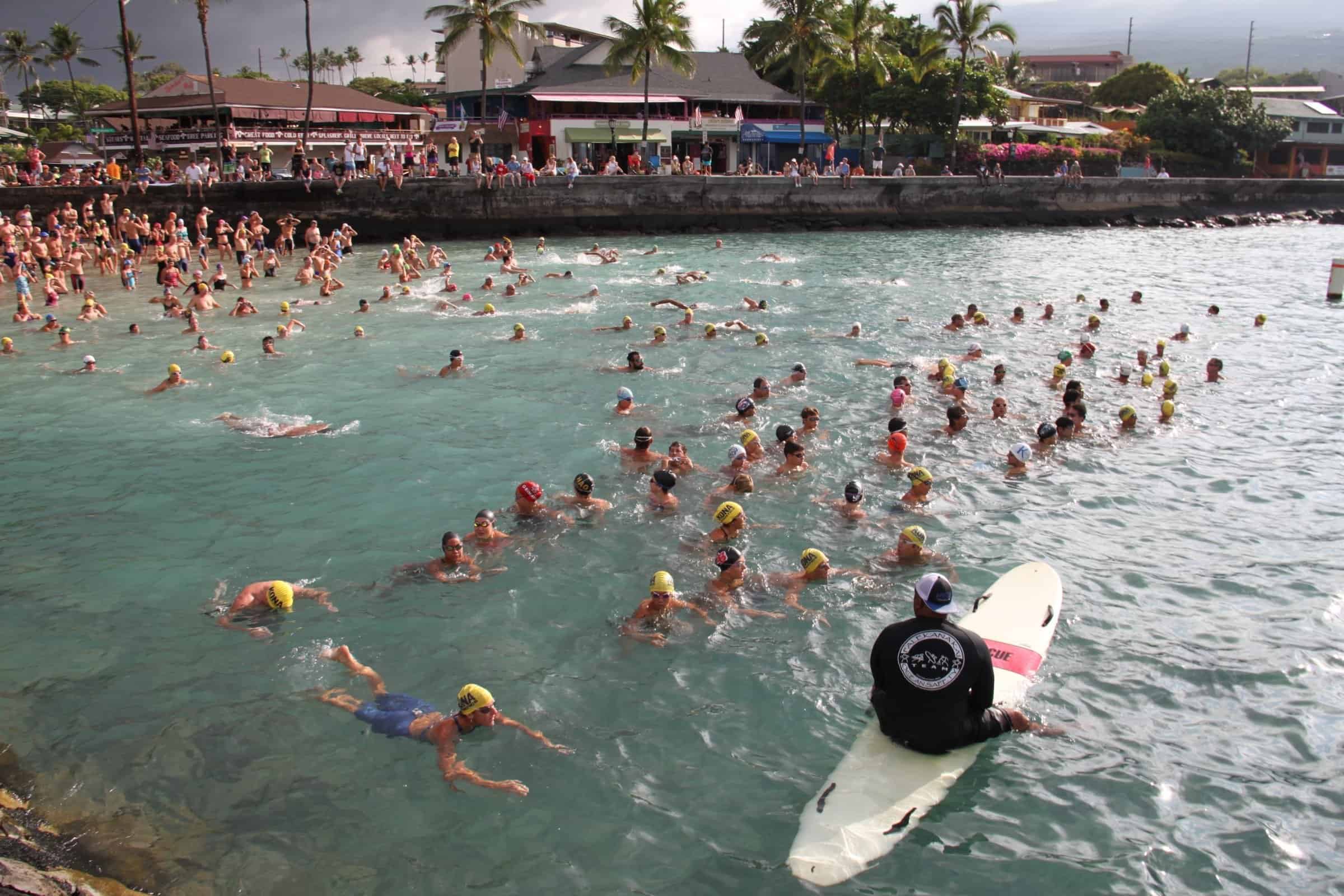 Overhead view of a mass swim start spreading out from the beach at a Kona open water race.