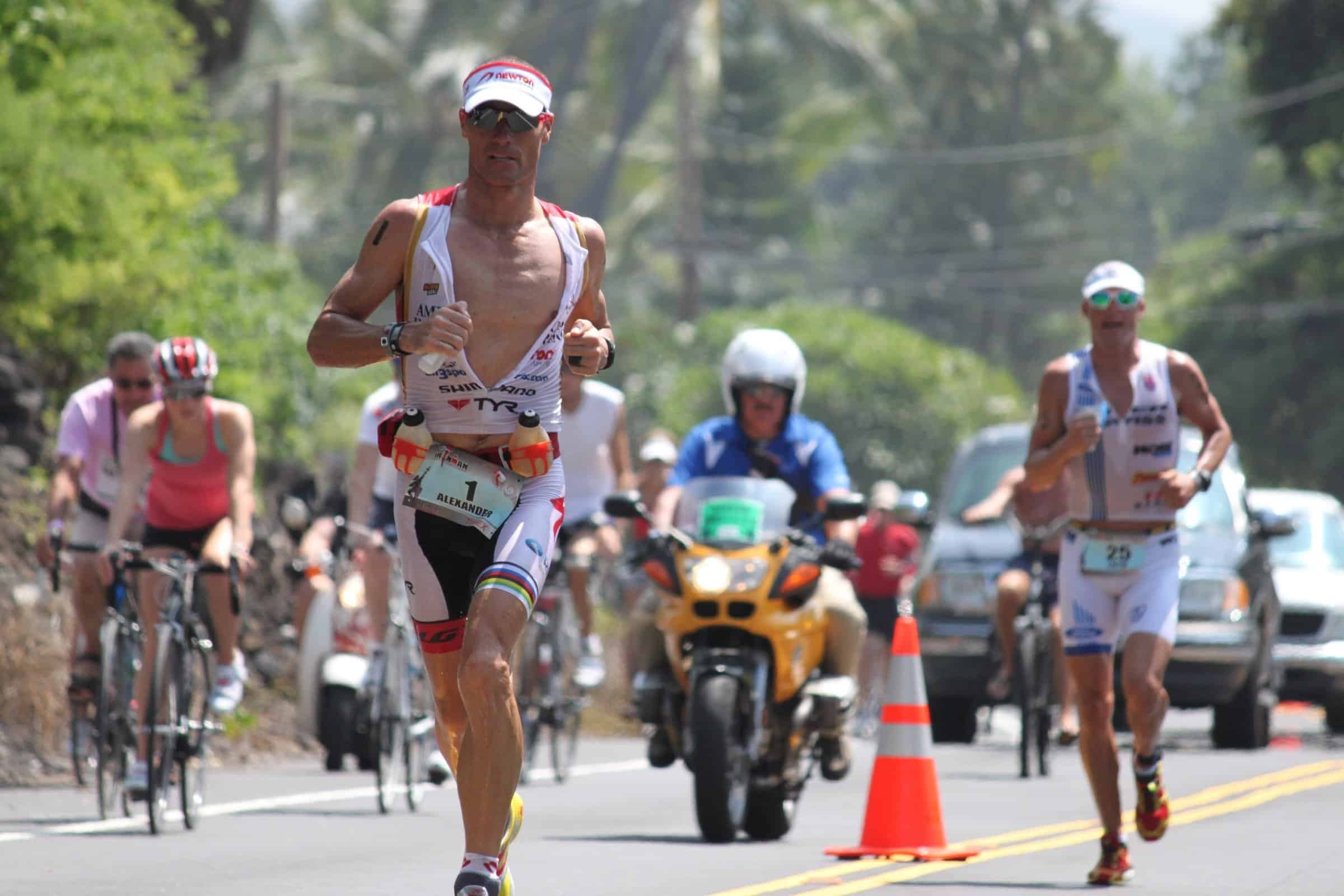 IRONMAN™ World Champion Craig Alexander running past cyclists on the World Championship course in Kona.